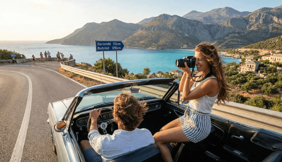 A couple in a convertible on a coastal road in Albania.